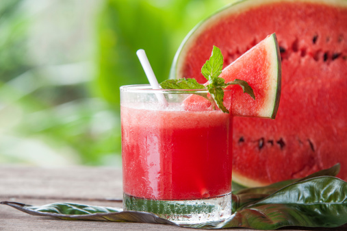 Watermelon smoothie in a glass placed on a wooden floor.