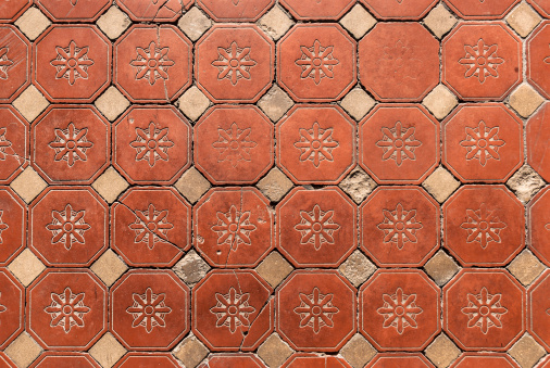 Old Victorian hexagonal floral pattern floor tiles showing wear.