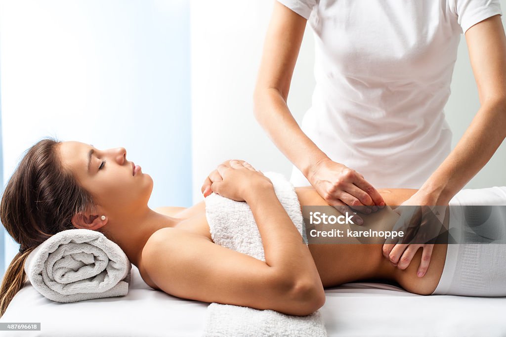 Therapist doing healing massage on female abdomen. Close up of osteopath doing manipulative massage on female abdomen. Massaging Stock Photo