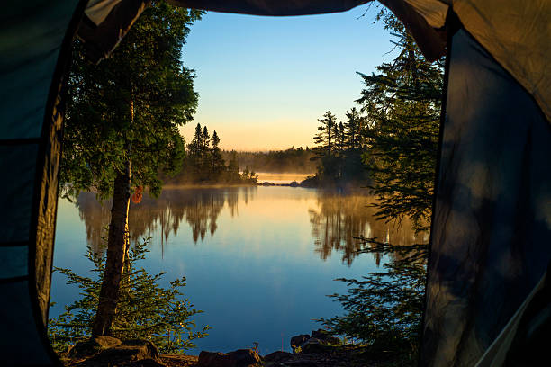looking out through the doorway of a tent onto morning mist and crescent lake, superior national forest, minnesota.