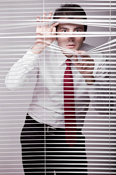 Man Watching through window blinds Man Watching through window blindsMan Watching through window blinds prowling stock pictures, royalty-free photos & images