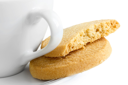 Detail of a white ceramic cup with shortbread biscuits.