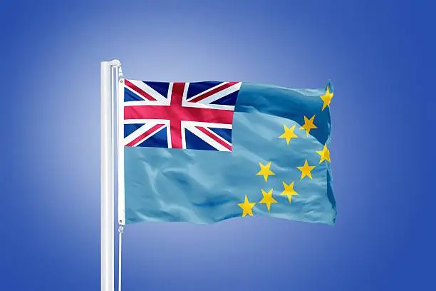 Photo of Flag of Tuvalu flying against a blue sky