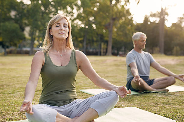 Clearing their minds Shot of a mature couple meditating outdoorshttp://195.154.178.81/DATA/i_collage/pu/shoots/805496.jpg yoga class photos stock pictures, royalty-free photos & images