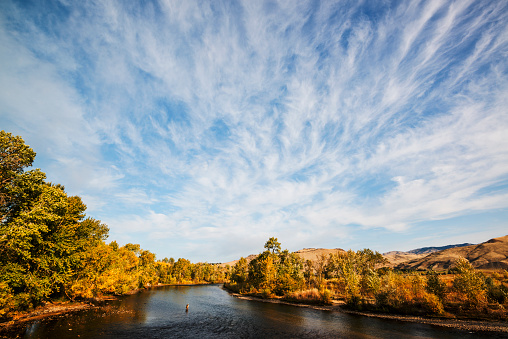 Beautiful and dramatic clouds over Boise River in Boise, Idaho on a fine autumn evening. I also included a person at the bottom of the frame who was busy fly fishing. Sky was so dramatic with the clouds, I minimized the river and dominated the frame with the beautiful sky