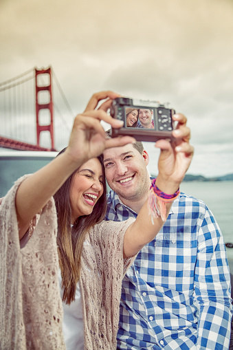 Cute attractive couple taking selfie photos at the Golden Gate Bridge