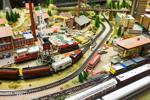 Vintage model electric train formed by a steam locomotive and green passenger cars on the rails