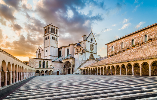 Famous Basilica of St. Francis of Assisi (Basilica Papale di San Francesco) with Lower Plaza at sunset in Assisi, Umbria, Italy.