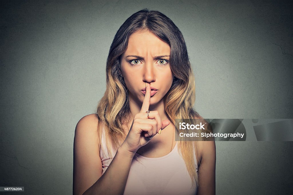 Portrait of beautiful woman with finger on lips gesture Portrait of beautiful woman with finger on lips isolated on gray background. Finger on Lips Stock Photo