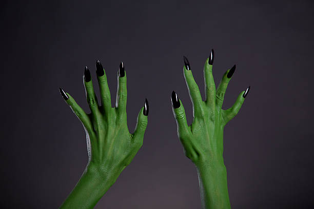 Green monster hands with sharp black nails, body-art stock photo
