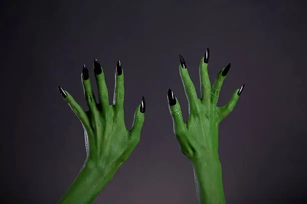 Green monster hands with sharp black nails, Halloween theme, studio shot on black background