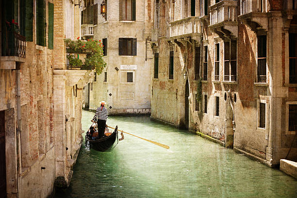 Gondola on canal in Venice Gondola travels down the canals of Venice in Italy gondolier stock pictures, royalty-free photos & images