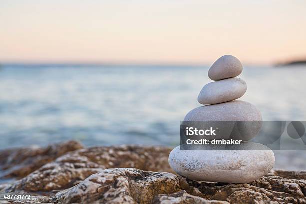 Pile Of Stones On Tranquil Beach At Sunset Stock Photo - Download Image Now - Stone - Object, Stack, Rock - Object