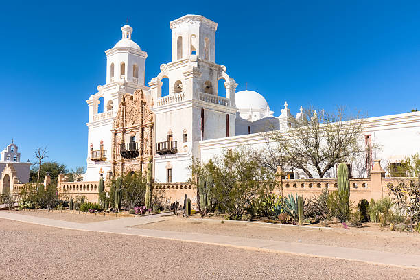 The historic Mission San Xavier del Bac situated on the Tohono O'odham Indian Reservation, affectionately known as “White Dove of the Desert,” stands in stark contrast to the clear blue cloudless sky.  Considered to be the finest example of Spanish Colonial architecture in United States, it has an elegant white stucco Moorish-inspired exterior with ornately decorated massive carved mesquite-wood doors, numerous bell towers and domes. The interior contains paintings, carvings, frescoes and statues of apostles and saints in dazzling colors. Gardens with native cacti and various succulents are strategically planted adding to the peace and tranquility of the Mission. It was declared a National Historic Landmark in 1960.