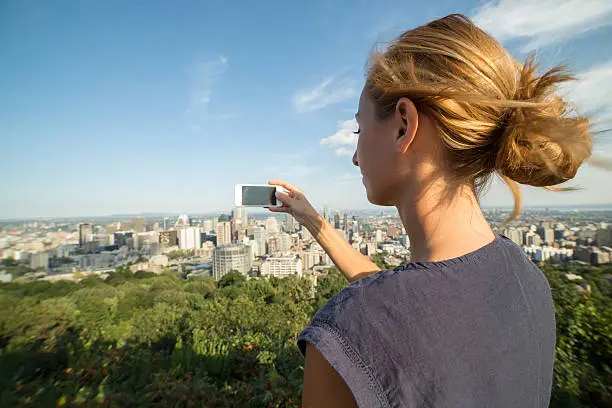 Photo of Young woman taking picture of Montreal cityscape