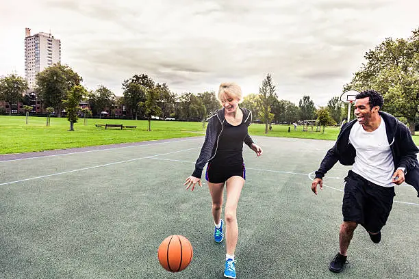 Basketball 1v1 man-woman in a London playground, UK.