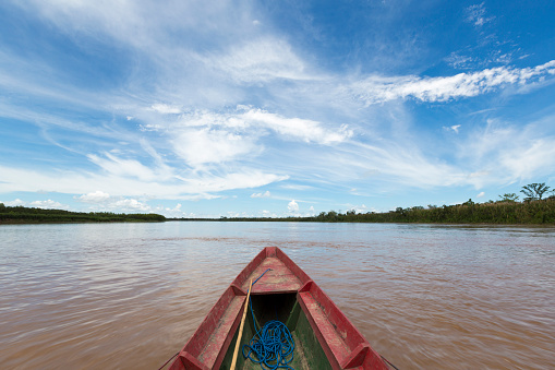 Traveling on a wooden boat on Beni river in Bolivian jungle near Rurrenabaque with blue sky in Madidi National Park. Bolivia
