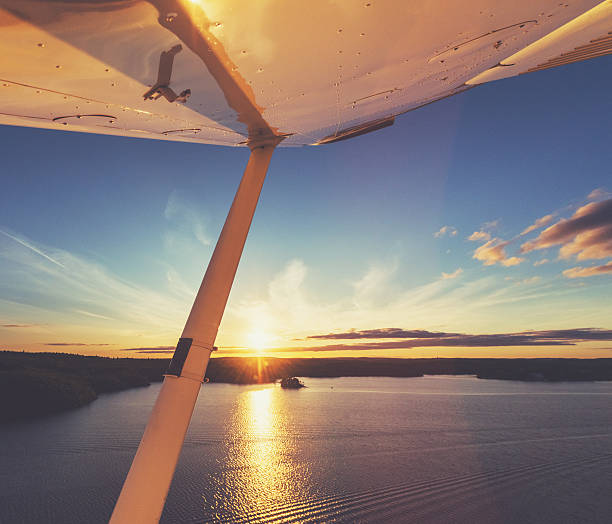 Flying in Evening Skies Flying low over a large lake bathed in the evening Sun. bush plane stock pictures, royalty-free photos & images