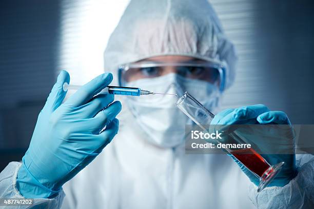 Researcher Preparing A Syringe For Injection Stock Photo - Download Image Now - 2015, Adult, Bib Overalls