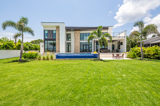 A beautiful modern home with landscaped backyard, swimming pool with waterfall and spa including an outdoor sitting area with TV.