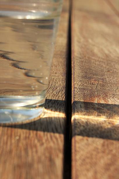 istock Half glass of water on wooden table 487745456