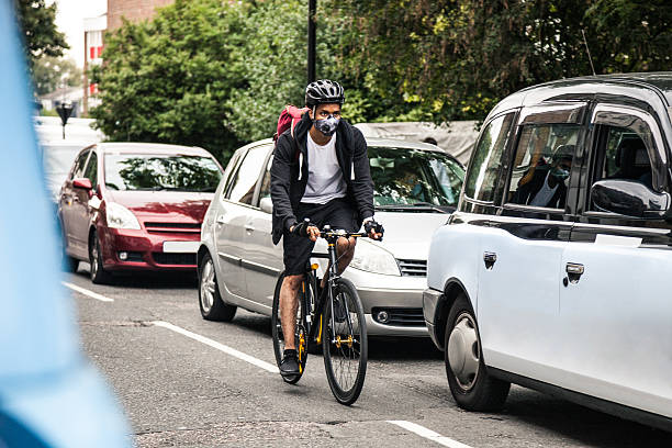 ciclista commuter usando una máscara de contaminación en el centro de londres - contaminación del aire fotografías e imágenes de stock