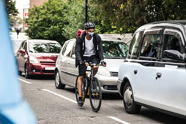 Cyclist commuter wearing a pollution-mask in Central London Cyclist commuter wearing a pollution-mask in Central London, while commuting to work in the morning. particulate stock pictures, royalty-free photos & images