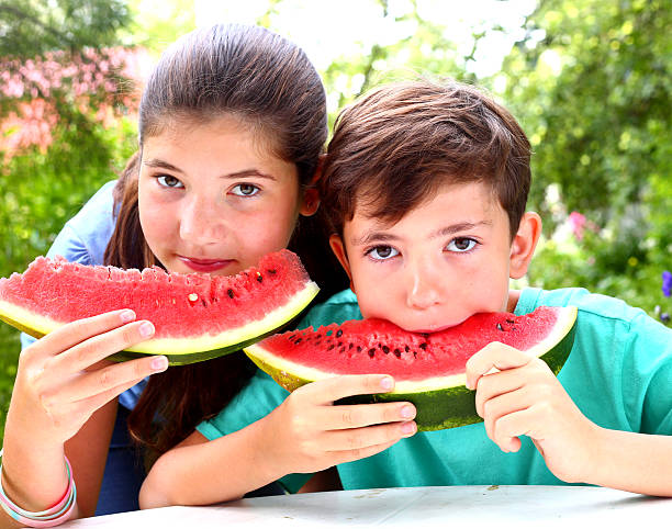 istock cute   siblings couple with water melon slices 487749218