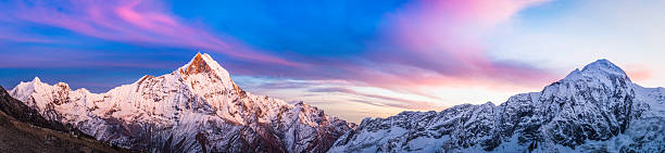 Gorgeous alpenglow sunset snowy peaks panorama Annapurna Sanctuary Himalayas Nepal Warm alpenglow light after sunset illuminating the snow capped summit pyramid of Machapuchare (6993m), the iconic unclimbed peak and sacred mountain deep in the Annapurna Conservation Area of the Nepal Himalaya. ProPhoto RGB profile for maximum color fidelity and gamut. annapurna circuit photos stock pictures, royalty-free photos & images