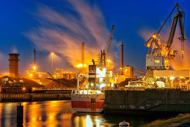 industrial plant, steelworks on the river illuminated at night, crane and ship moored at the wharf, Amsterdam, Netherlands