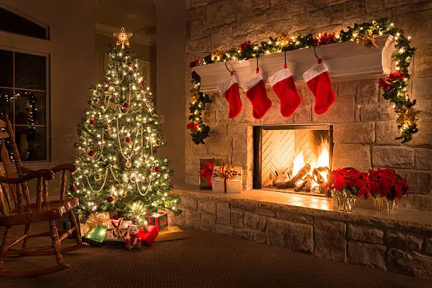 Photo of Christmas. Glowing fireplace, hearth, tree. Red stockings. Gifts and decorations.