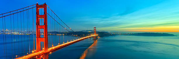 Golden Gate Bridge Photograph of Golden Gate Bridge shortly after sunset. This is panoramic view of Golden Gate. Bridge is brightly illuminated and located on left side of photograph with colorful sunset sky. san francisco bay stock pictures, royalty-free photos & images