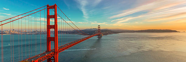 Golden Gate Bridge Photograph of Golden Gate Bridge shortly after sunset. This is panoramic view of Golden Gate. Bridge is brightly illuminated and located on left side of photograph with colorful sunset sky. golden gate bridge stock pictures, royalty-free photos & images