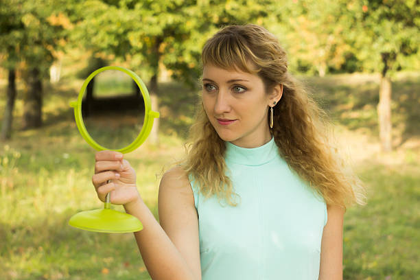 istock Young beautiful girl look into mirror in the park. 487761030