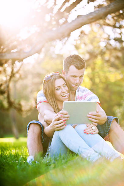 istock Young couple joking with a digital tablet in the park 487765822