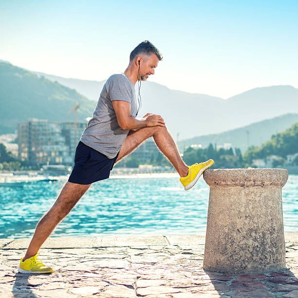 Always stretch Man exercising and stretching legs on pier running jogging men human leg stock pictures, royalty-free photos & images