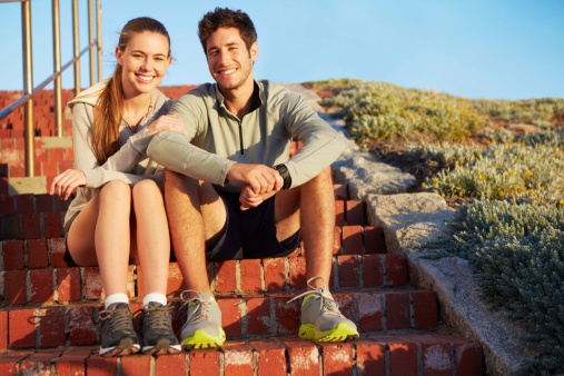 A young couple sitting on the stairs taking a break from their morning jog