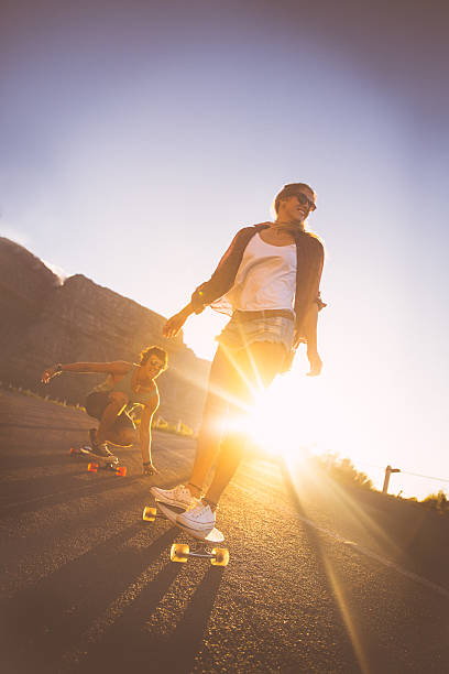 istock Couple skateboarding on road in sunset 487774015