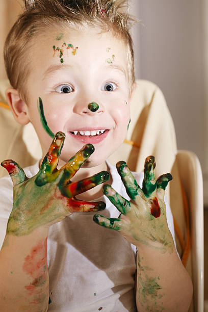 istock Cute excited boy with hands full of finger paint 487781149