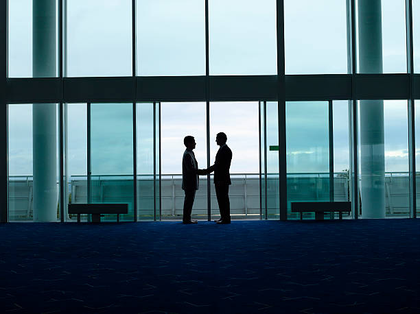 istock Silhouette Businessmen Shaking Hands At Airport 487786769