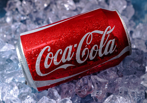 Minsk, Belarus - August 16, 2015: Minsk, Belarus - August 16, 2015: Can of Coca-Cola on a bed of ice over a blue background