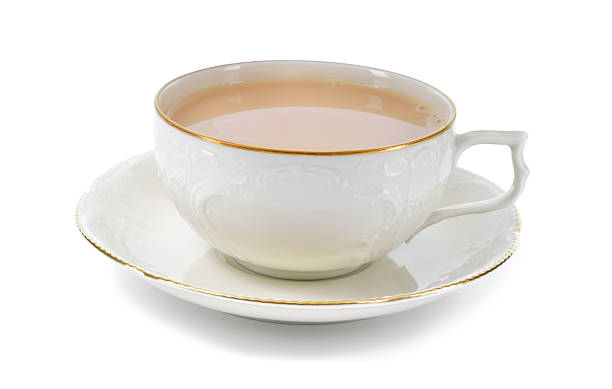 Black tea with milk in a porcelain cup. Tea with milk in antique porcelain cup isolated on white background. Porcelain cup and saucer with delicate relief structures and gold decoration. tea cup and saucer stock pictures, royalty-free photos & images