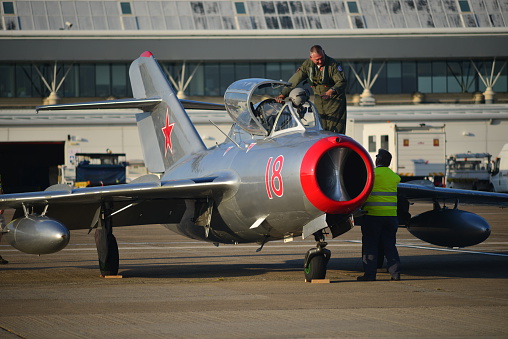 Jersey, U.K. - September 9, 2015: The Russian MIG 15 arrives at Jersey airport for the annual air display for the following day. The pilot is just leaving the cockpit and preparing the aircraft with an engineer for an overnight stay. A vintage aircraft which took part in the Korean War in the 50's and said to be one of the best and most produced jet fighters ever.