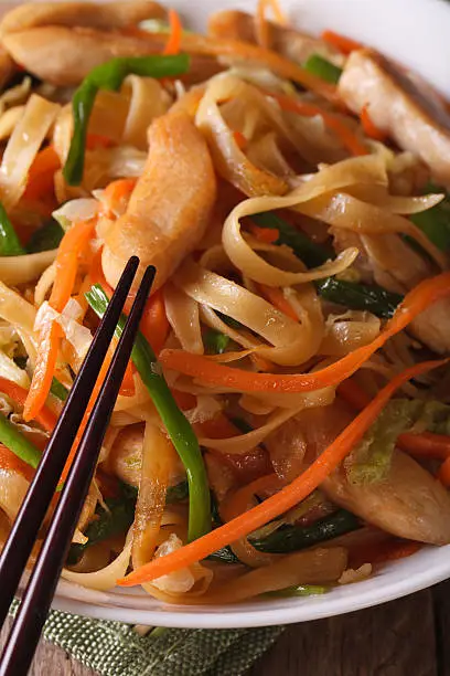 Photo of fried noodles with chicken and vegetables macro. vertical