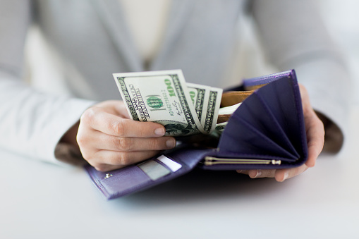 business, finance, saving, banking and people concept - close up of woman hands with wallet and us dollar money