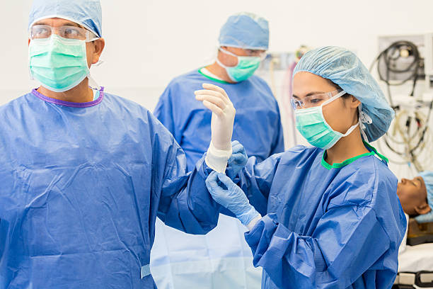 enfermera ayudando a cirugía cirujano con guantes, traje de u - hair net nurse scrubs asian ethnicity fotografías e imágenes de stock
