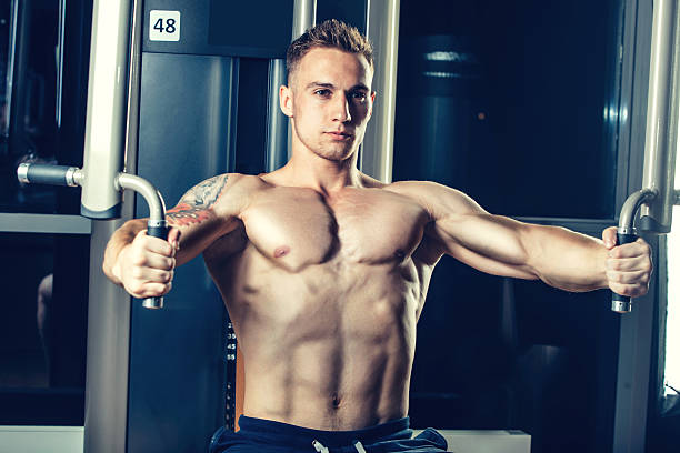 istock Brutal athletic man pumping up muscles on crossover 487797254