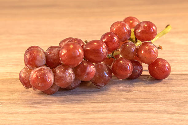 grapes Grapes lying on a wooden surface, with a spider crawing accross them animall stock pictures, royalty-free photos & images