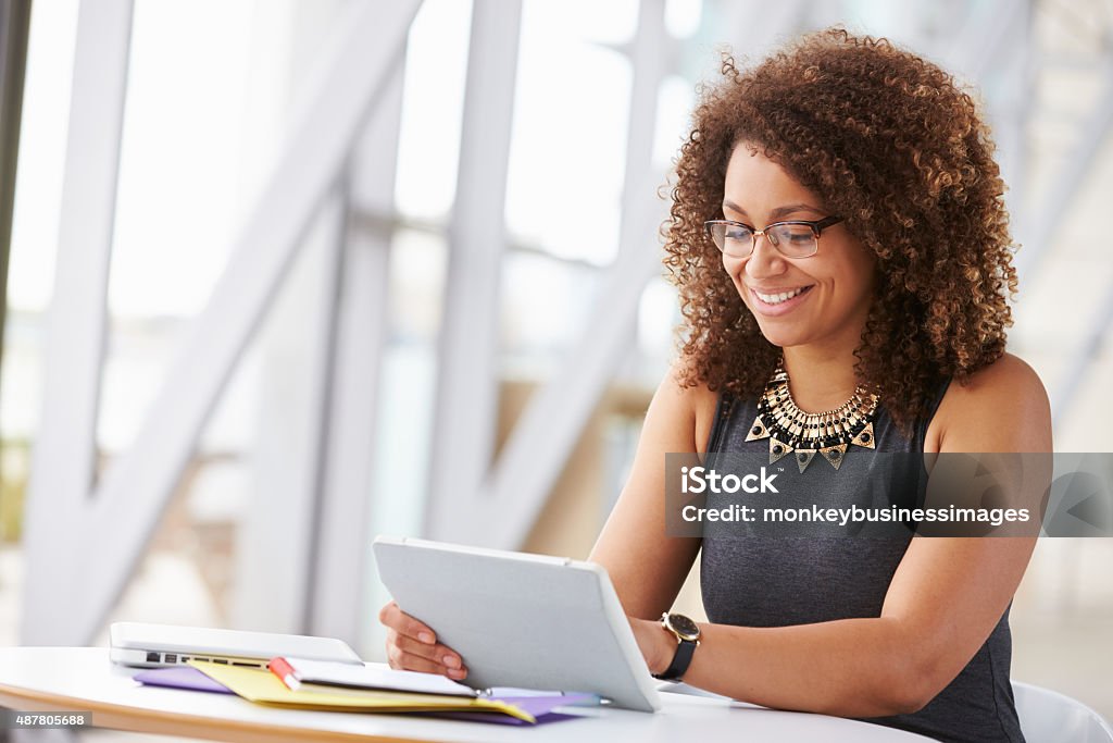 Jovem mulher afro-americana com tablet no escritório trabalhando - Foto de stock de Mesa digital royalty-free