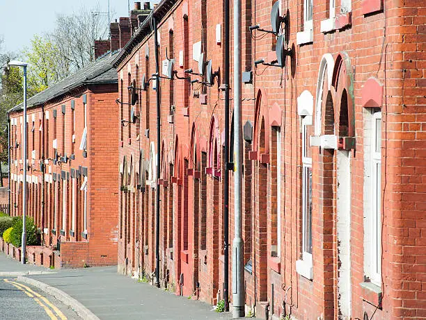 Compressed perspective view of a row of red bricked terraced houses in the northern town of Oldham situated in Greater Manchester.